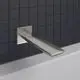 Wandauslauf in Edelstahloptik von Ideal Standard, rechteckig mit flacher Auslaufkante, montiert an einer glatten Wand mit dunklen Fliesen.